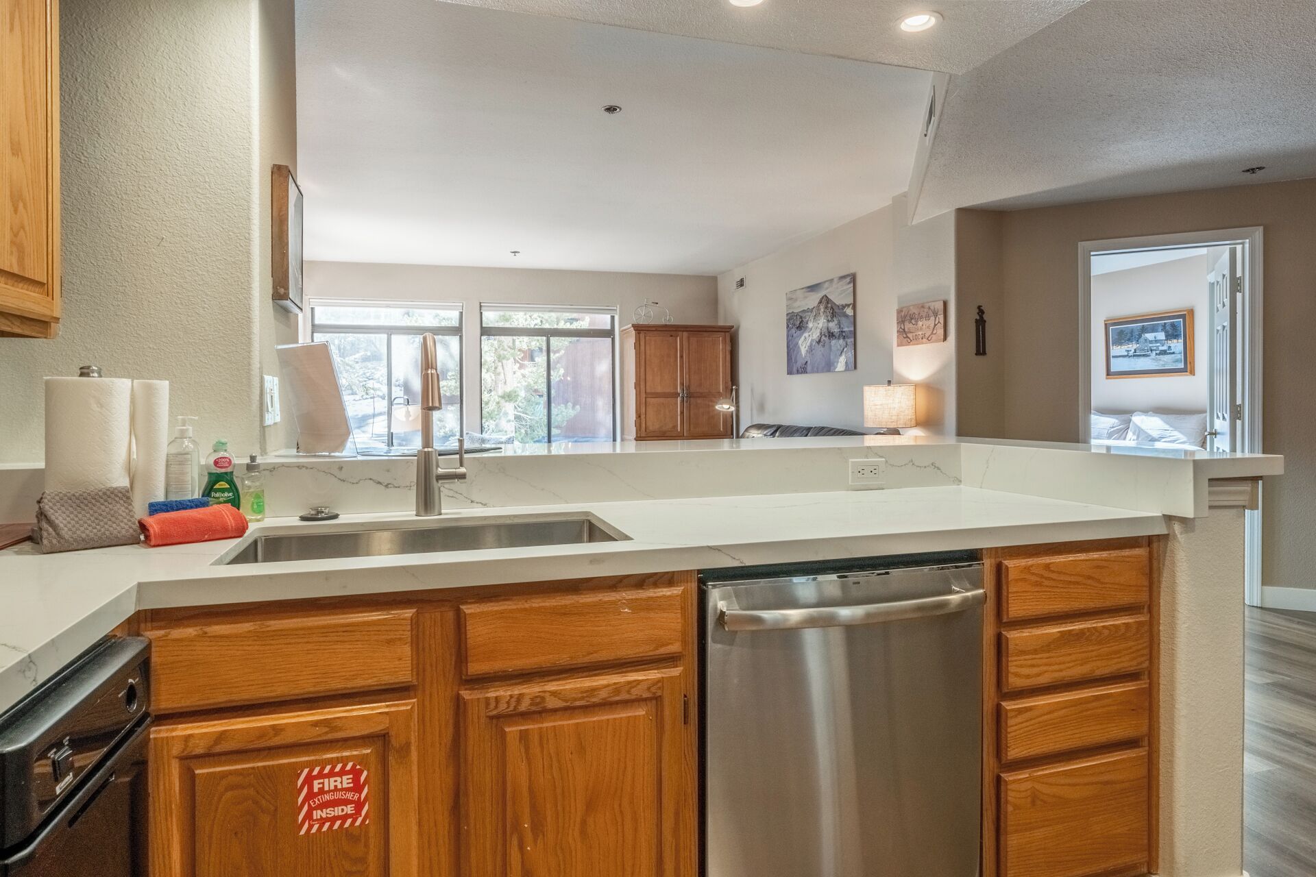 A modern kitchen with wooden cabinets, a stainless steel dishwasher, and a large island with a sink.