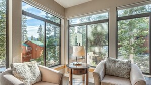 A room with large windows, two armchairs, a small table, and a lamp.