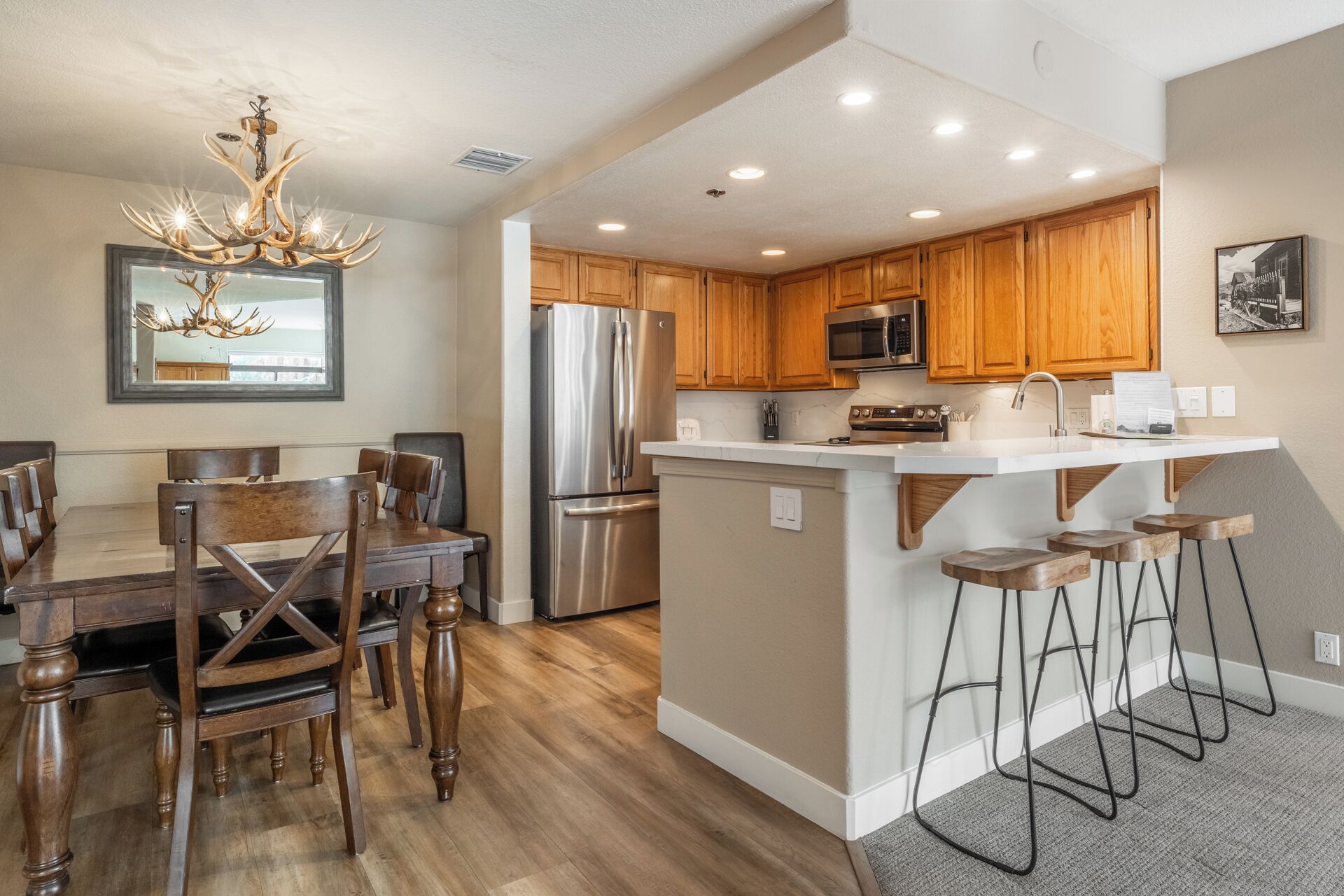 A modern kitchen with wooden cabinets, stainless steel appliances, and a bar stool area.