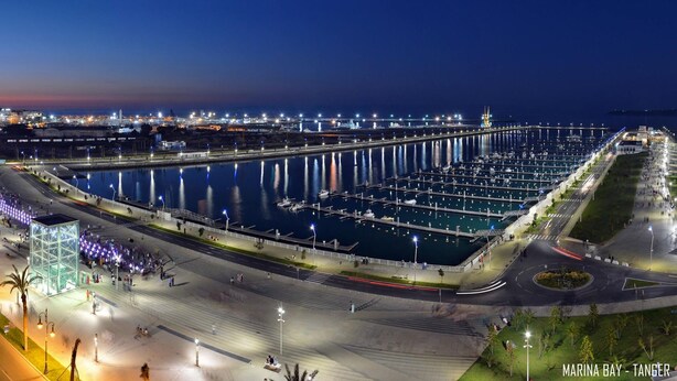 Un port de plaisance avec des quais et des bateaux, une promenade piétonne et un pont.