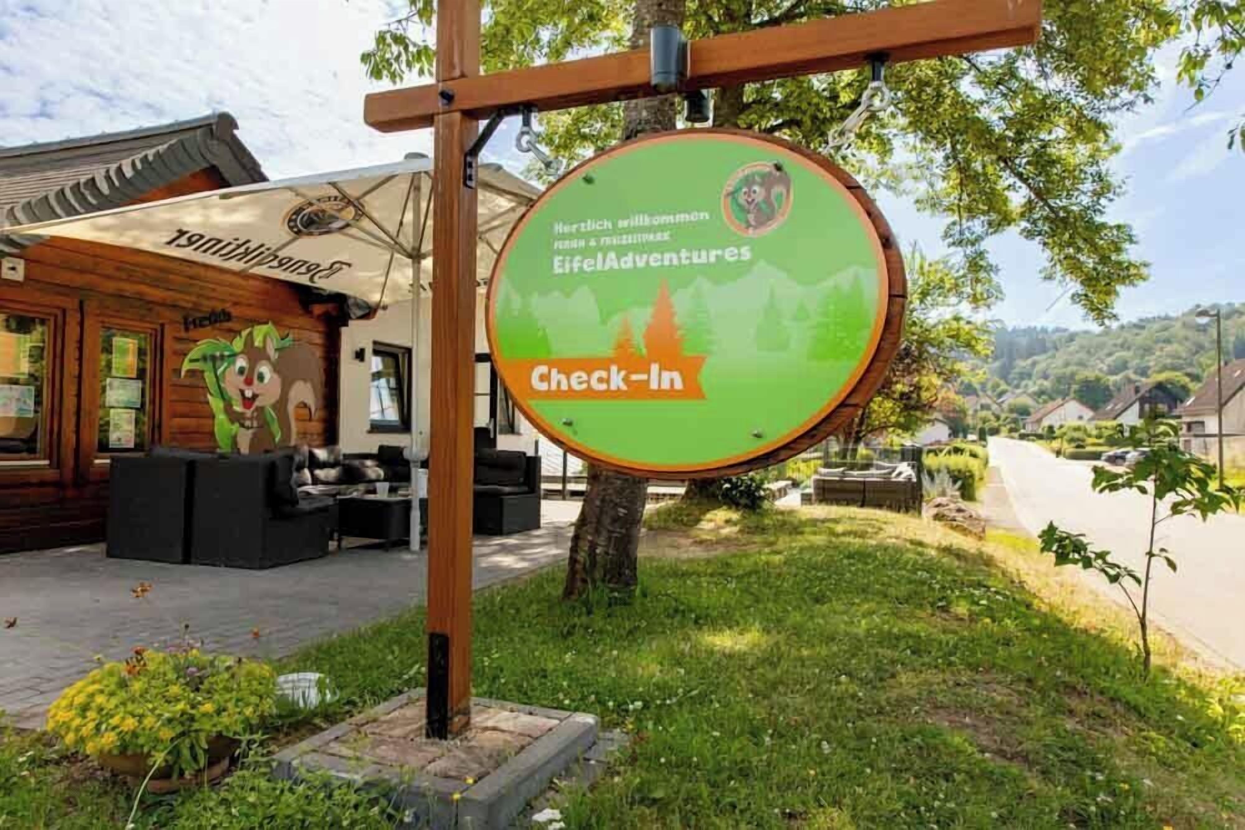 A wooden building with a sign for 'Eifel Adventures' and a 'Check-In' area.