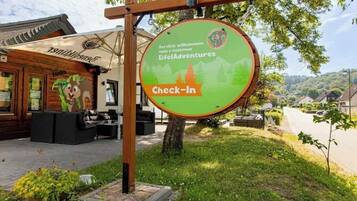 A wooden building with a sign for 'Eifel Adventures' and a 'Check-In' area.