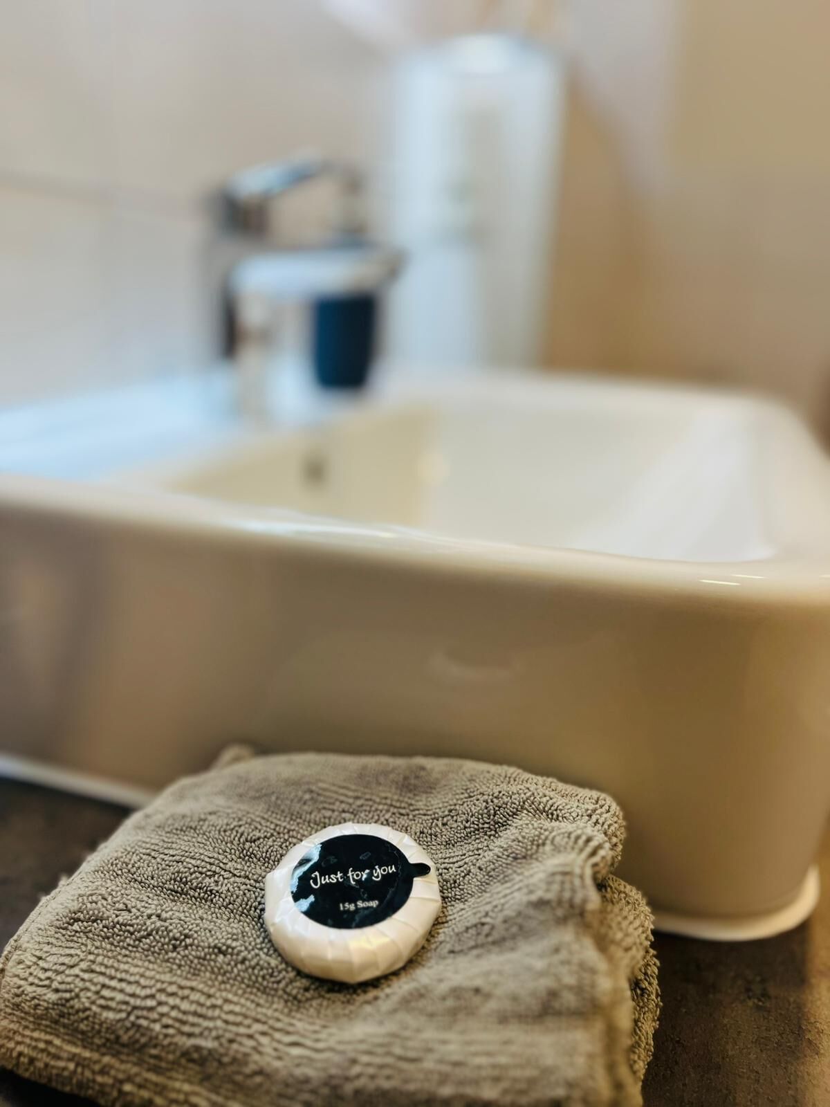Un lavabo de salle de bain avec une bouteille de savon étiquetée « Savon spécialement pour vous, 15 g » posée sur une serviette.