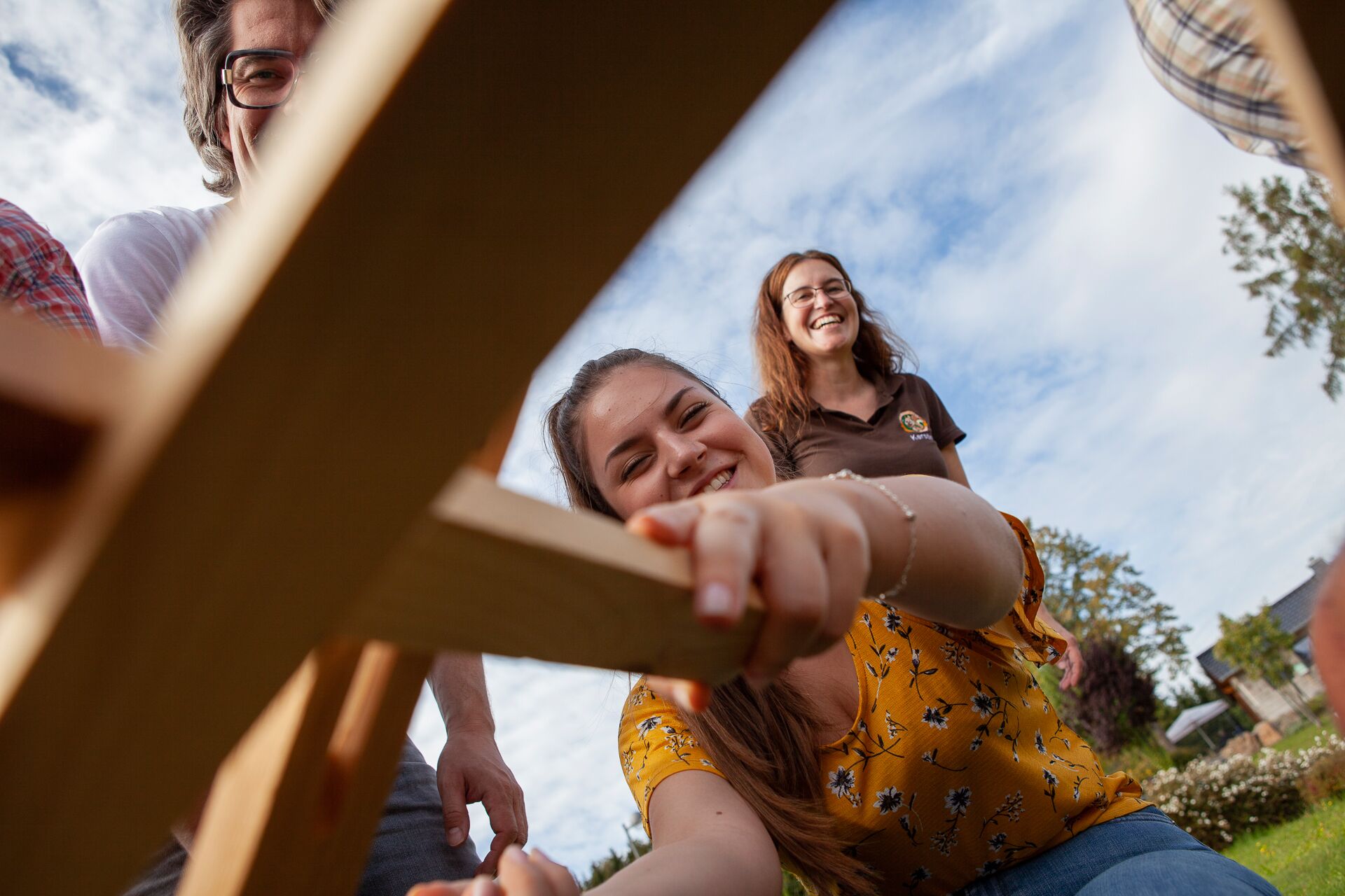 Un grupo de personas sentadas al aire libre con una estructura de madera al frente.