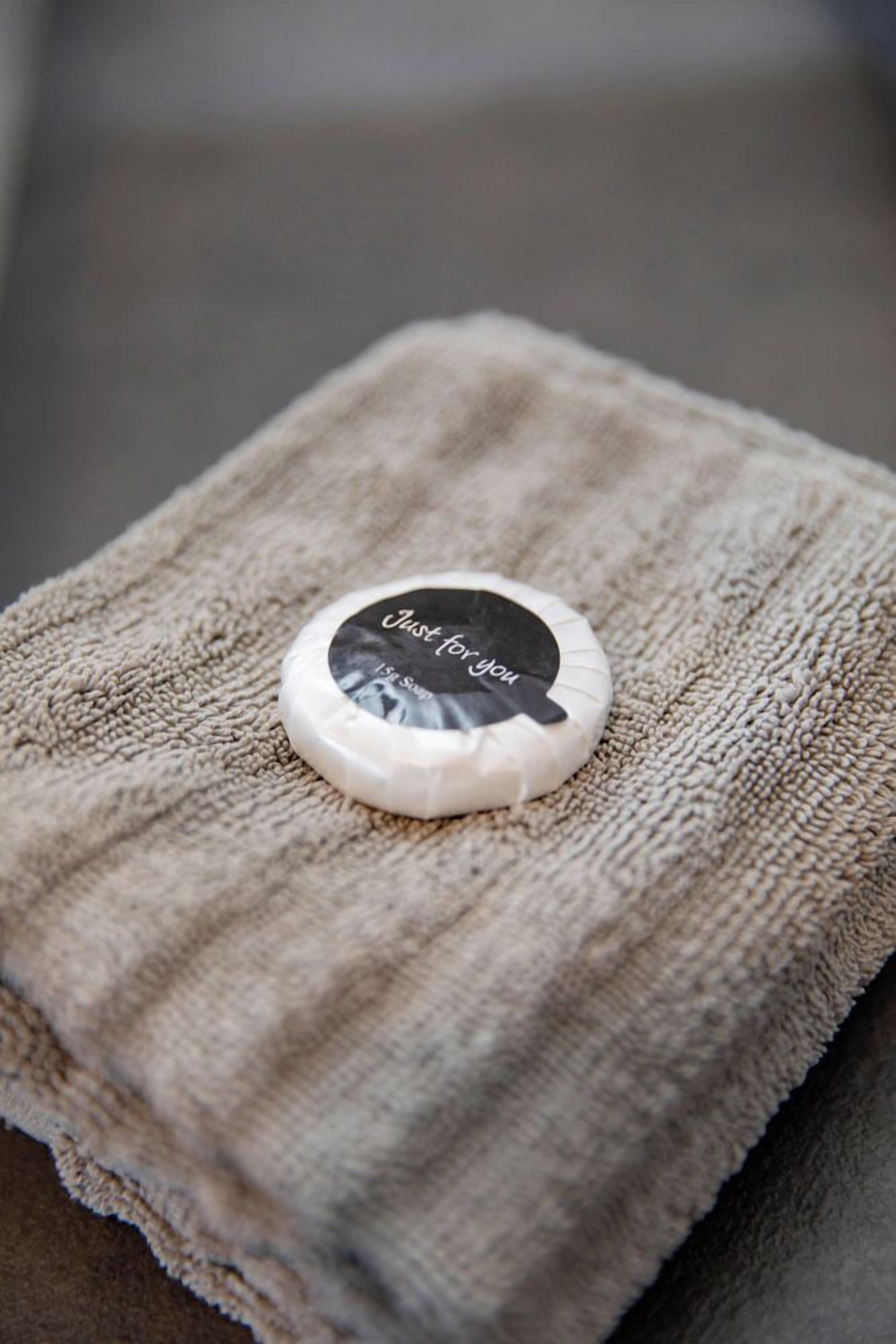 Un objet rond et blanc, orné d’une étiquette noire, posé sur une serviette beige à texture.