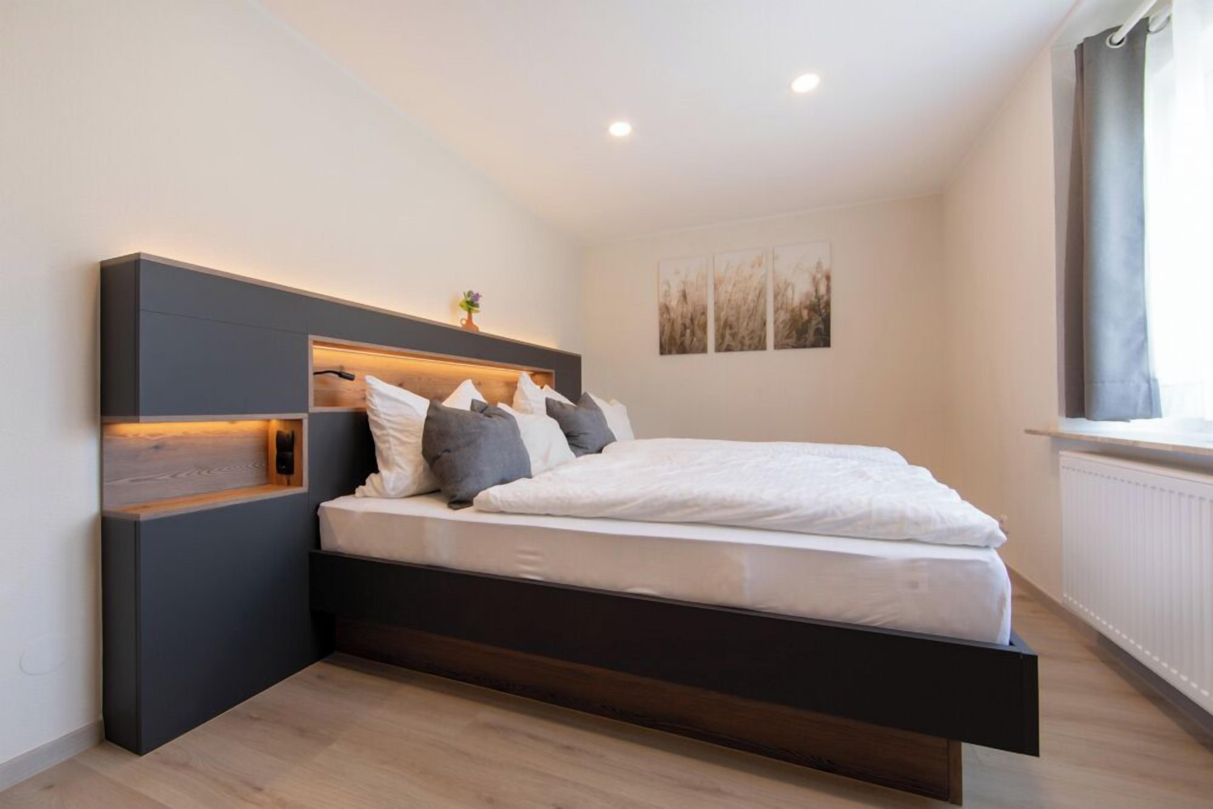 A modern bedroom with a built-in bed, bedside tables, and a window with curtains.