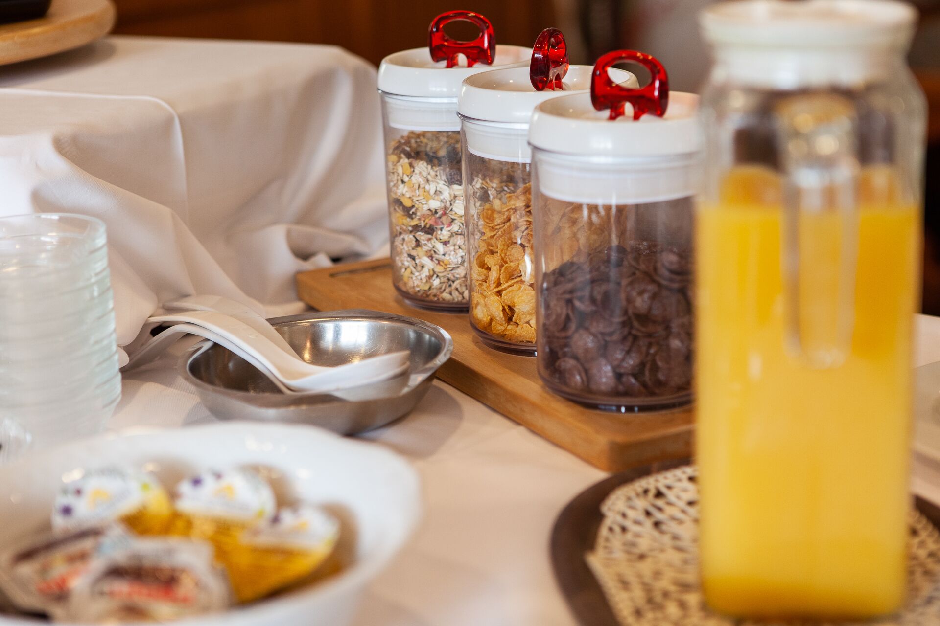 A breakfast buffet setup with various food items and a juice dispenser.