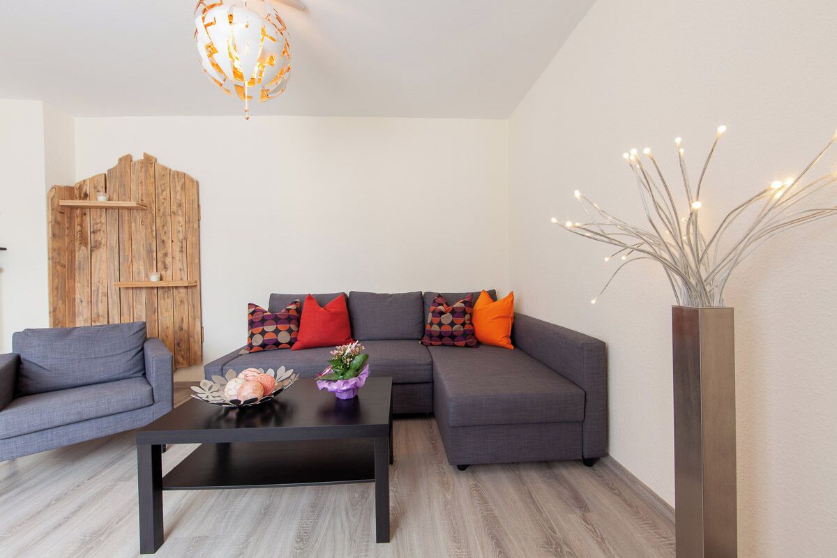 Una sala de estar moderna con un sofá modular, una mesa de centro y un jarrón decorativo.