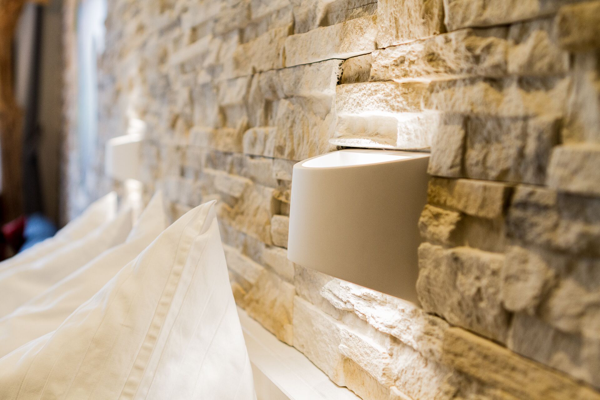 A stone wall with a white cylindrical object, possibly a light fixture, mounted on it.