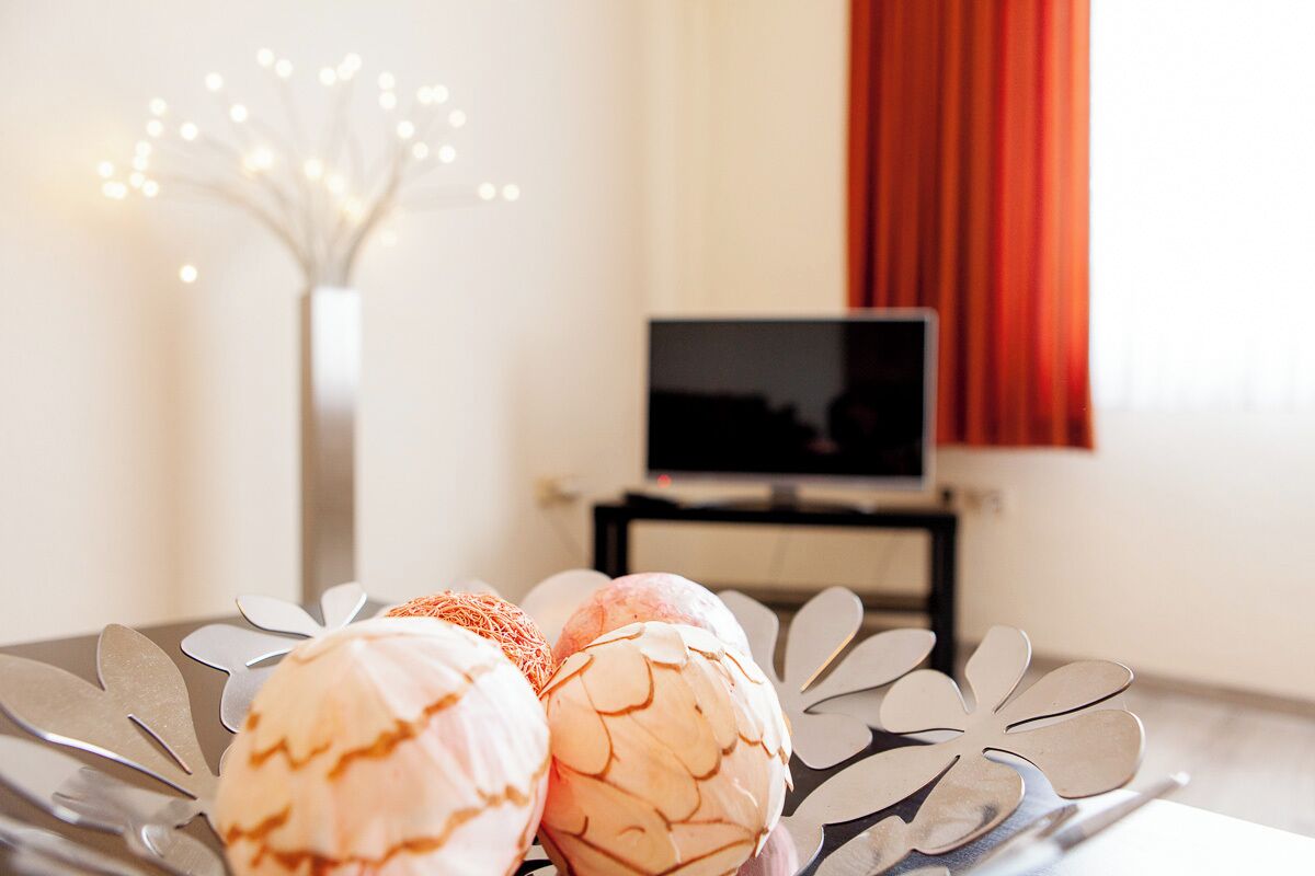 A dining table with a decorative centerpiece and a television in the background.