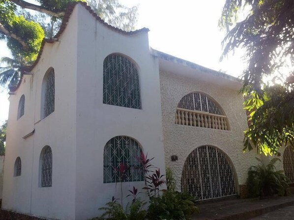 A white building with arched windows and a large arched entrance. - Dream of Africa Cottages Kanamai (Mtwapa)