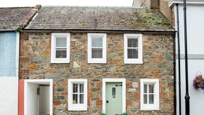 A stone building with three windows and a green door, featuring a traditional architectural style. - 4 bedroom accommodation in Kirkcudbright (Kirkcudbright)