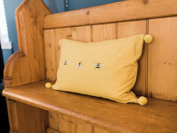 A wooden bench with a yellow cushion featuring embroidered bees. - 4 bedroom accommodation in Kirkcudbright (Kirkcudbright)