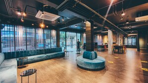 A modern interior with a seating area, wooden flooring, and large windows. - Hotel Ordinary Bangkok (Bangkok)