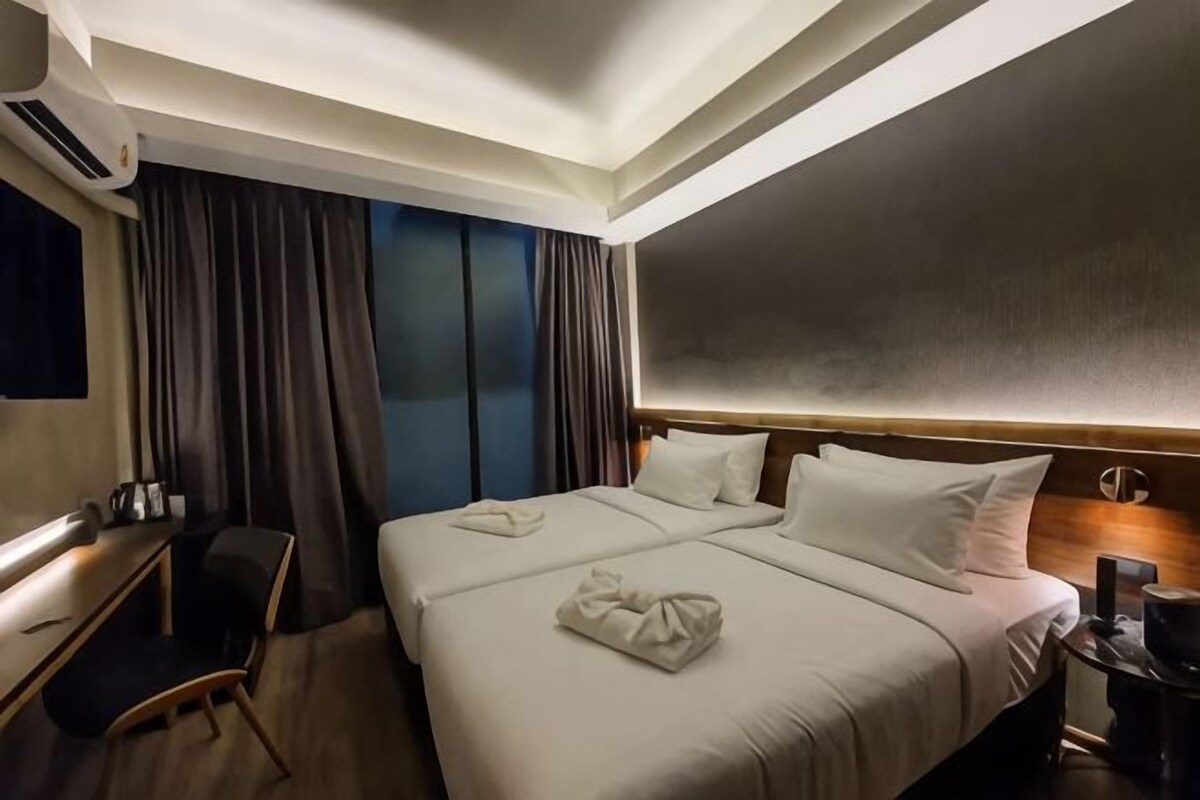 A hotel room with a large bed, a desk, and a TV.