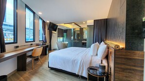 A modern hotel room with a large bed, a desk, a chair, a flat-screen TV, and a bathroom with a mirror and sink. - Hotel Ordinary Bangkok (Bangkok)