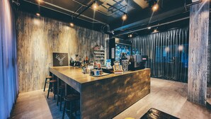 A modern bar area with a wooden counter, stools, and a barista station. - Hotel Ordinary Bangkok (Bangkok)