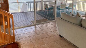 A wooden interior with a sliding glass door leading to a balcony overlooking the sea. - Remember When, Old Florida Beach House (Cayo Costa)