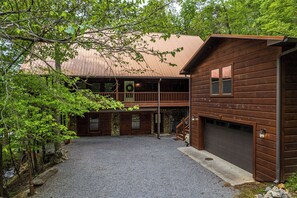 A two-story log cabin with a covered porch and a garage.