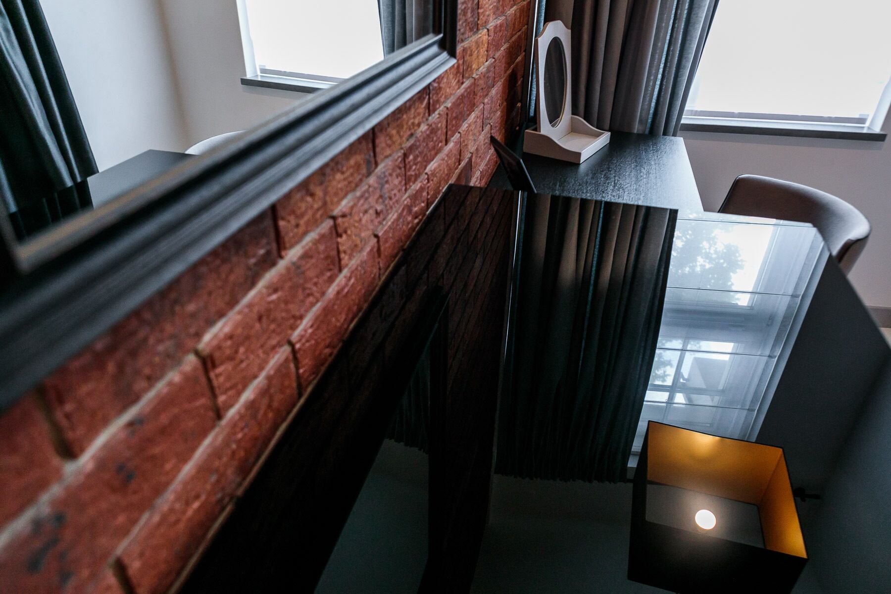 A modern interior with a brick wall, a dark wooden table, and a glass partition.