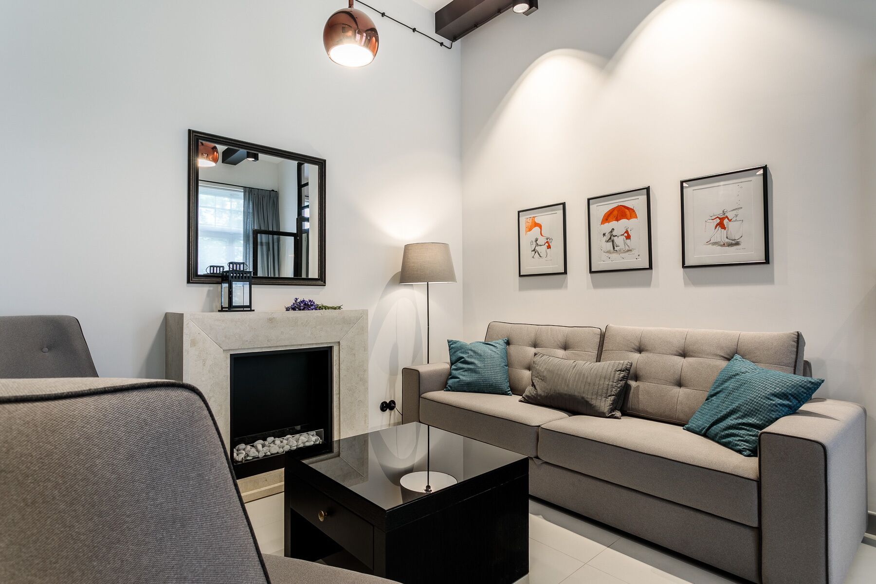 Una sala de estar moderna con sofá, una mesa de centro, chimenea, espejo y obras de arte enmarcadas en la pared.