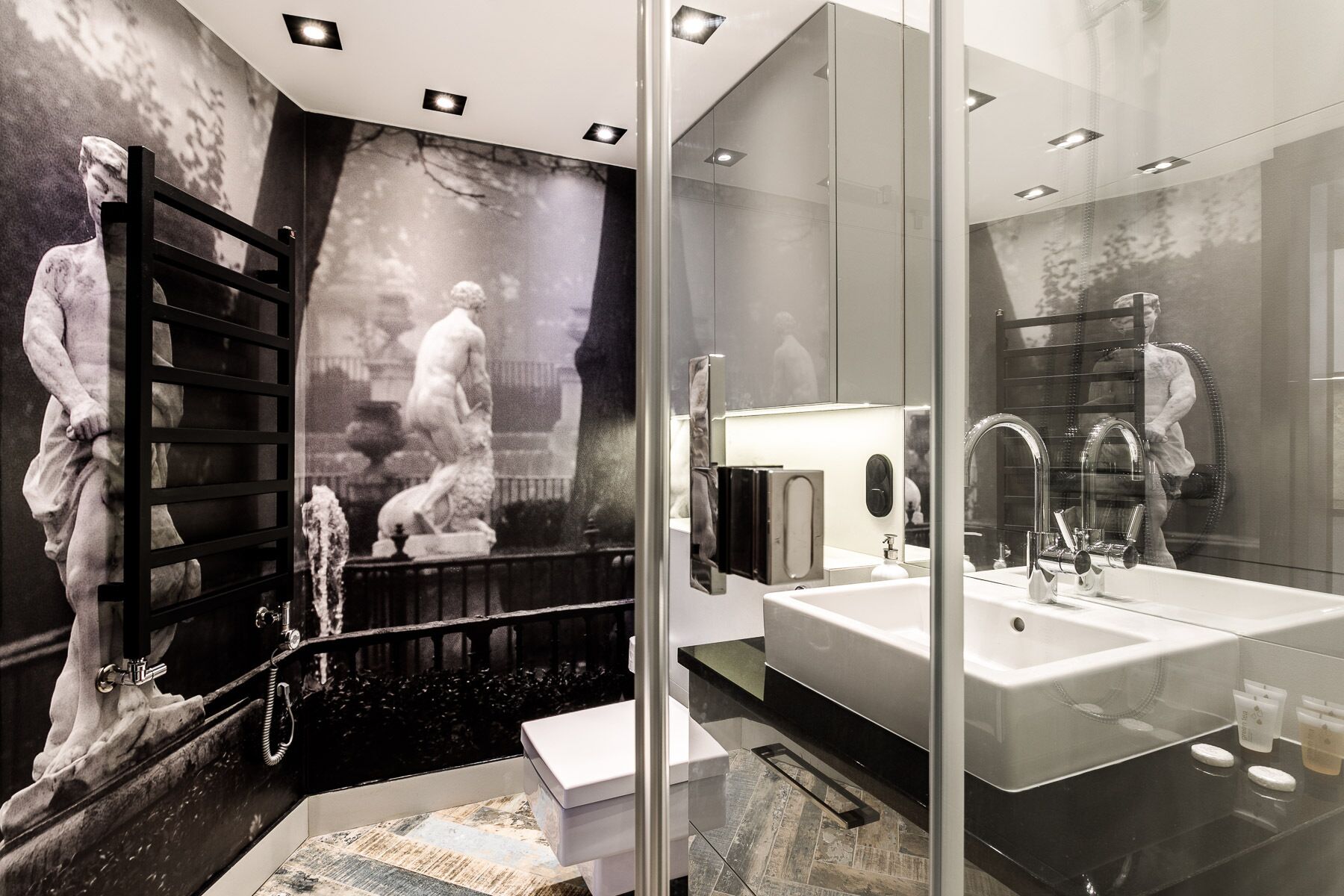 A modern bathroom with a large mirror, a glass shower enclosure, and a marble-tiled floor.
