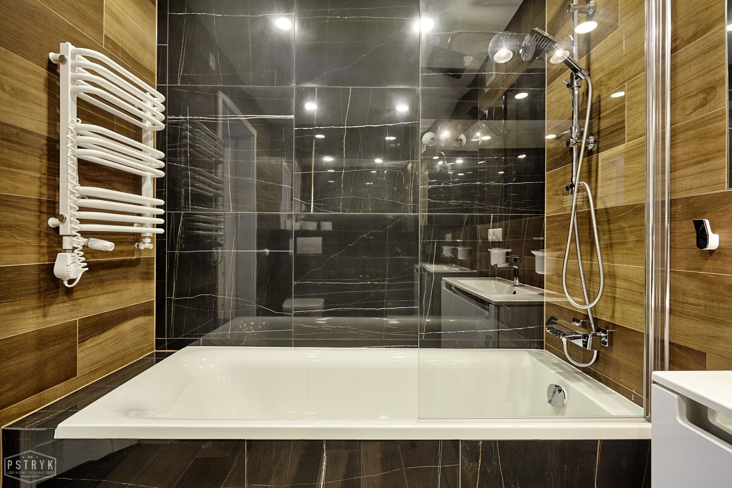 Une salle de bain moderne avec une grande baignoire, un espace de douche clos par des parois de verre et un porte-serviettes blanc.