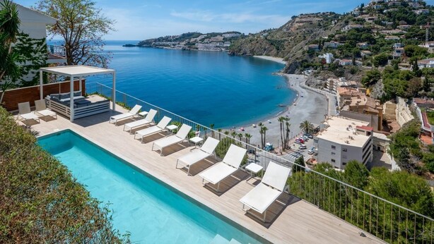 A pool area with lounge chairs and a view of the coastline. - Lovely modern villa with private heated pool (Almuñécar)