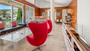 A modern interior with a dining area, red chairs, a white table, and a view of the outdoors. - Lovely modern villa with private heated pool (Almuñécar)