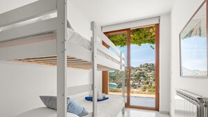 A modern bedroom with bunk beds, a large window with a view of a hillside, and a radiator. - Lovely modern villa with private heated pool (Almuñécar)