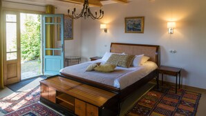 Un dormitorio con una cama grande, cabecera de madera, mesitas de noche, un candelabro y vistas al exterior.
