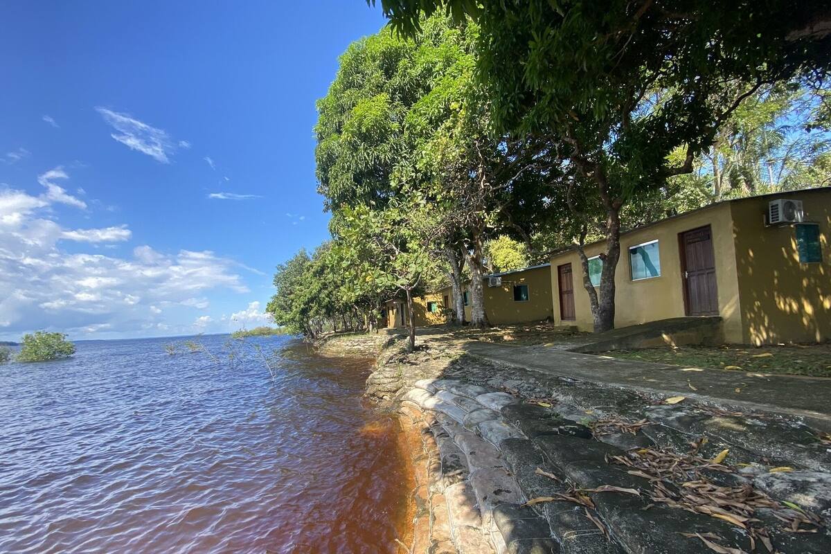 A coastal building with stone steps leading to a wooden door, overlooking a body of water.
