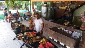 A buffet setup with various food items and a man standing behind it. - Anaconda Amazon Resort (Manaus)