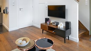 Een moderne woonkamer met een trap, een flatscreen televisie, een salontafel en een zithoek.