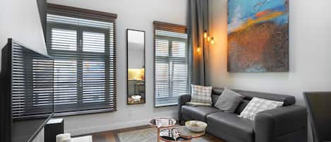 A modern living room with a grey sofa, a coffee table, and a large abstract painting.