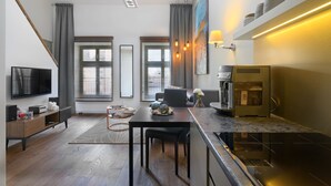 Een moderne keuken met een inbouwoven, een eethoek met een tafel en stoelen, en een groot raam met zonwering.