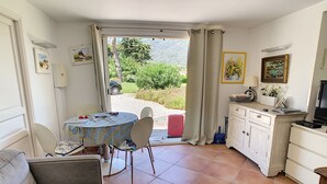 A cozy living room with a dining area, a kitchen, and a sliding glass door leading to a garden.