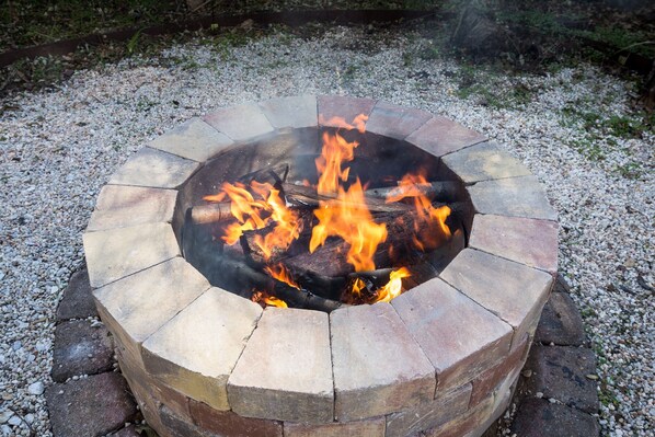 A circular stone fire pit with burning logs and flames.