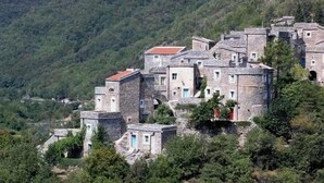 A cluster of stone buildings with a mountainous backdrop, likely a historical or rural accommodation area.