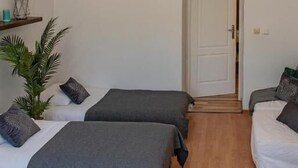 A room with two beds, a wooden floor, a white door, and hanging pendant lights. - 3D WAWEL Apartament (Kraków)