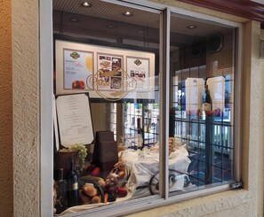 Vitrina de restaurante mostrando un menú, una copa de vino y diversas frutas y verduras.