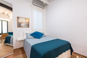 Ein Hotelzimmer mit Bett, Fenster, Gemälde und Stuhl.