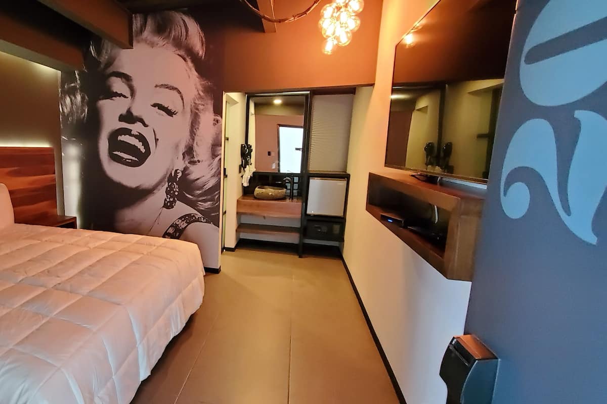 A bedroom with a large bed, a mirror, and a wall mural.