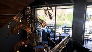 Un interior moderno con una planta grande, una escalera y vistas al exterior.