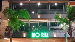 Un edificio moderno con un llamativo letrero de neón verde que dice "RIO RITA" y un gran logotipo con la letra "R".