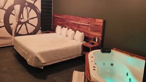 Un dormitorio con cama, cabecero de madera, mesita de noche, aire acondicionado de pared y bañera con revestimiento de madera.