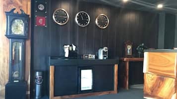 Una habitación con pared de madera, una barra negra con una cafetera y tres relojes.