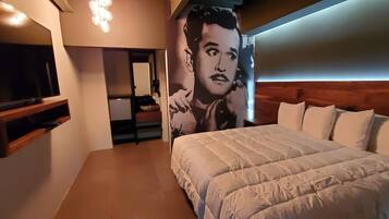 Un dormitorio con una cama grande, un televisor montado en la pared y un cartel en la pared.