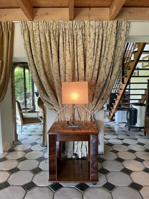 Relax in this inviting room with a wooden table, hexagonal tile floor, and a view of lush greenery.