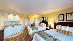 A hotel room with two beds, a kitchenette, a dining area, and a bathroom.